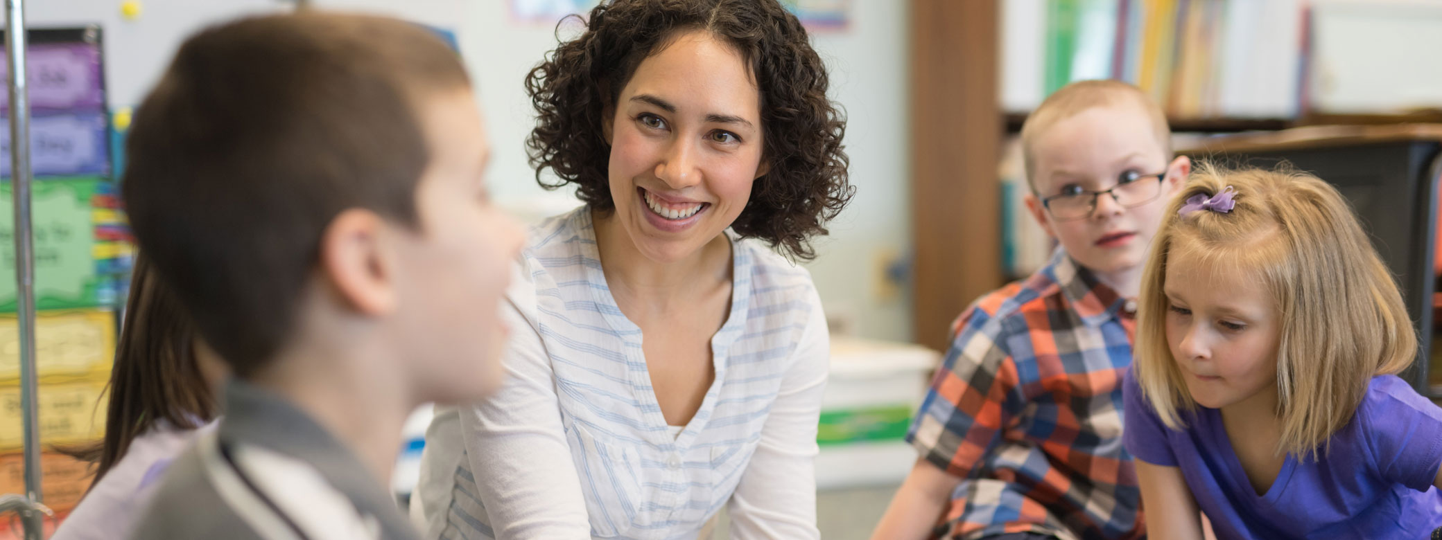 Kinder sitzen mit Erzieherin zusammen und reden
