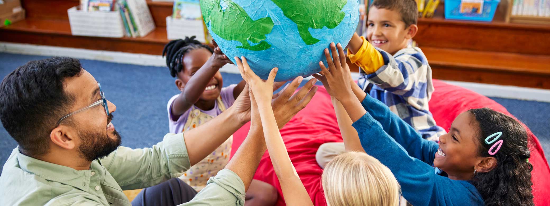 Kinder und Erzieher halten einen Erdball